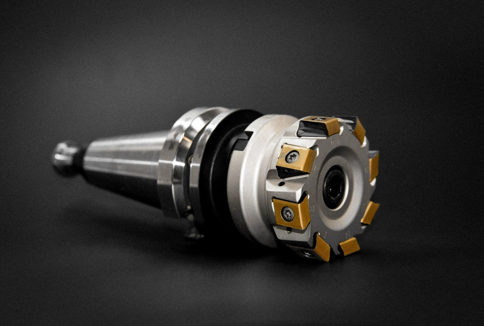 Metallwerkzeug mit auswechselbaren gelben Schneidplatten auf schwarzem Hintergrund.