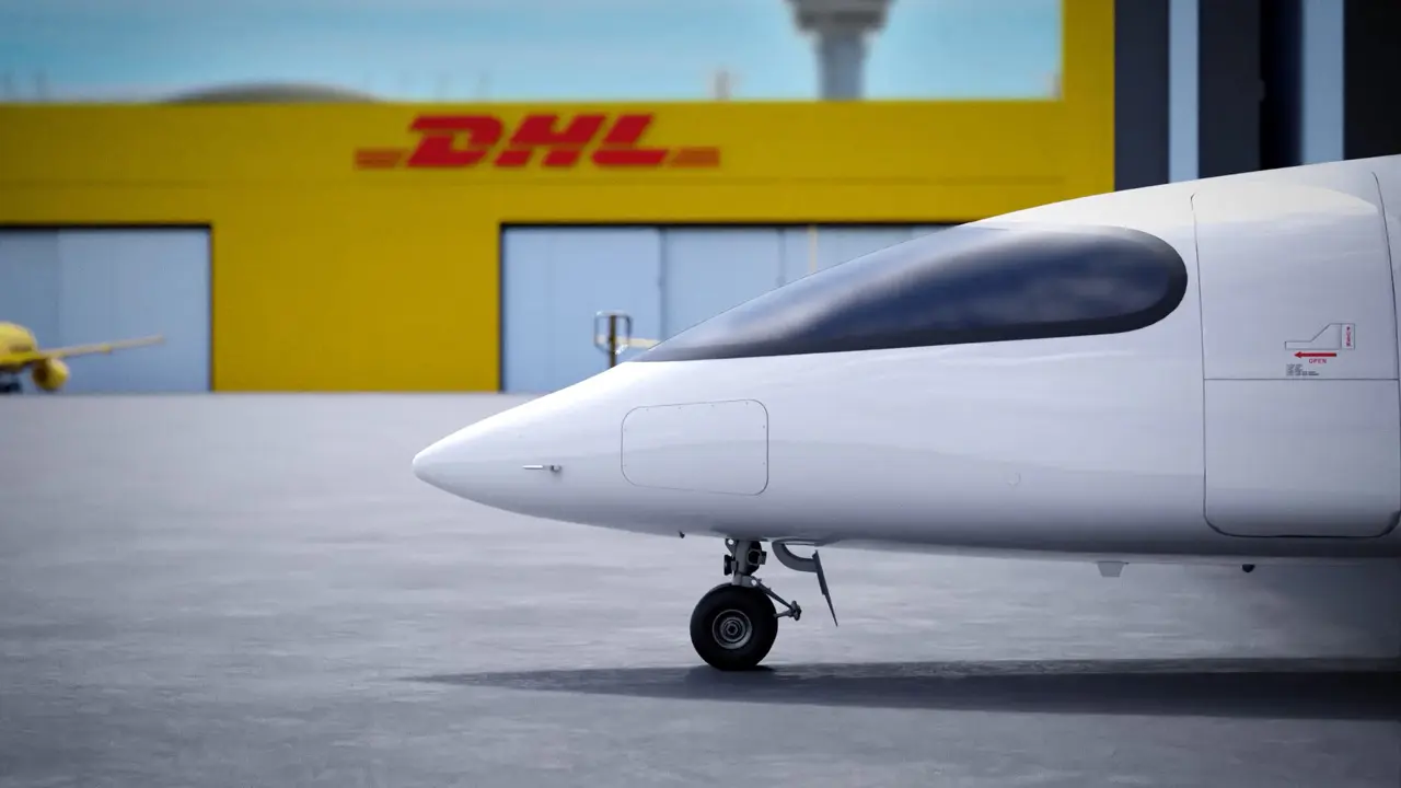 Nase eines weißen Flugzeugs vor einem gelben DHL-Gebäude an einem Flughafen.