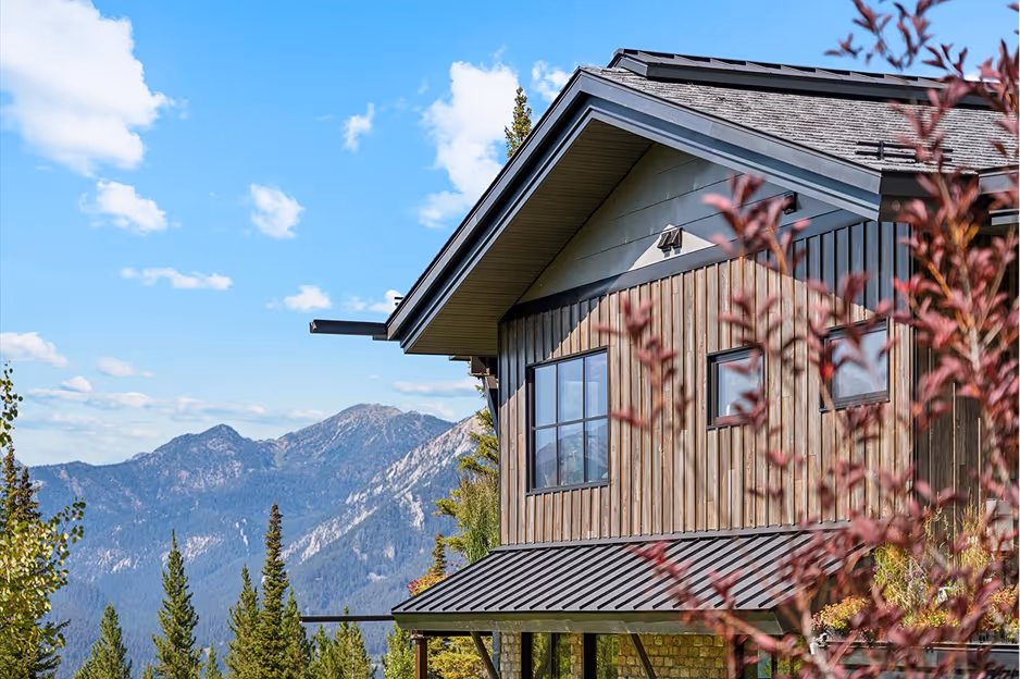 Outdoor view of two rows of storage units with green roll-up doors under a partly cloudy blue sky.