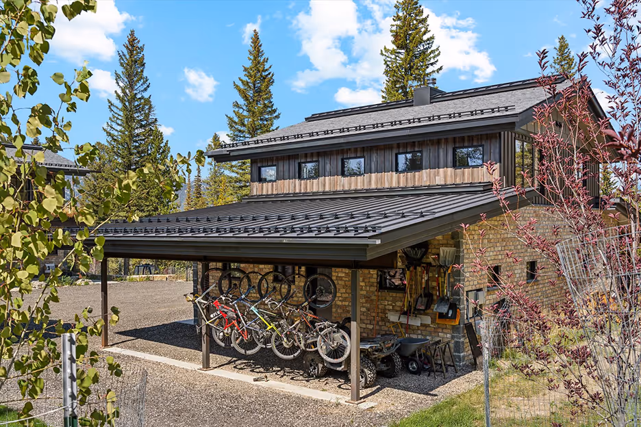 Modern backyard with a rectangular pool, water features, white seating, and a covered outdoor kitchen with grill and bar stools.