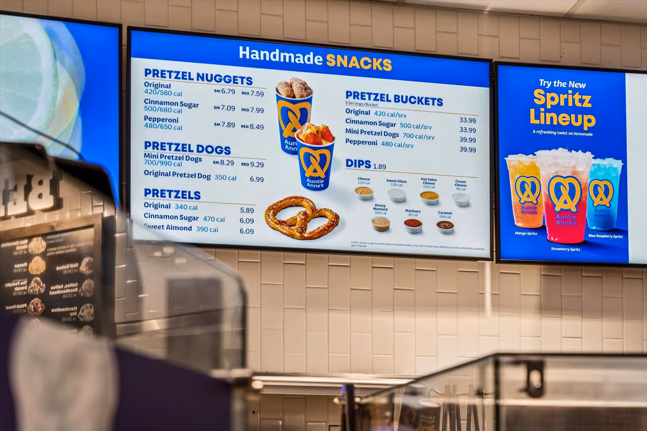 Auntie Anne's menu board displaying handmade snacks including pretzel nuggets, pretzel dogs, pretzels, pretzel buckets, dips, and the new Spritz lineup of flavored lemonades.