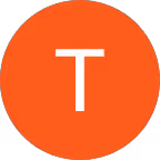 Smiling woman with long blonde hair wearing a white sleeveless top, posing outdoors near a body of water and greenery under a clear blue sky.