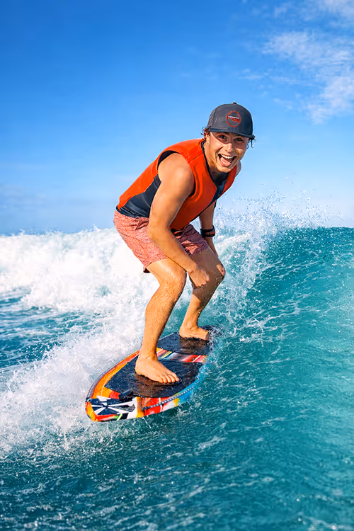 Three women relaxing on a boat seat with a city skyline and blue water in the background under a partly cloudy sky.