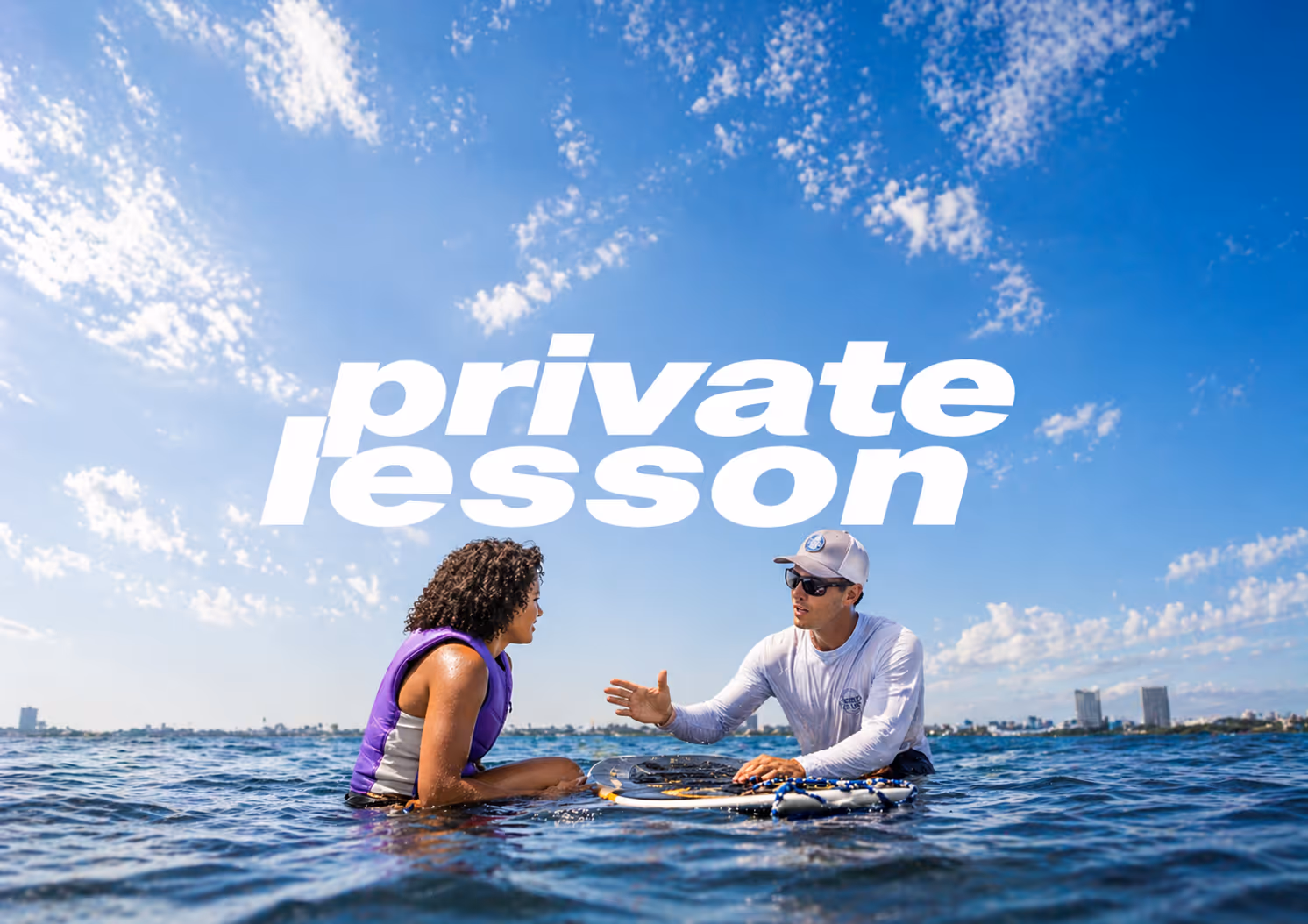 Woman in purple swimsuit surfing on a wave under a bright blue sky with the text 'open sessions'.