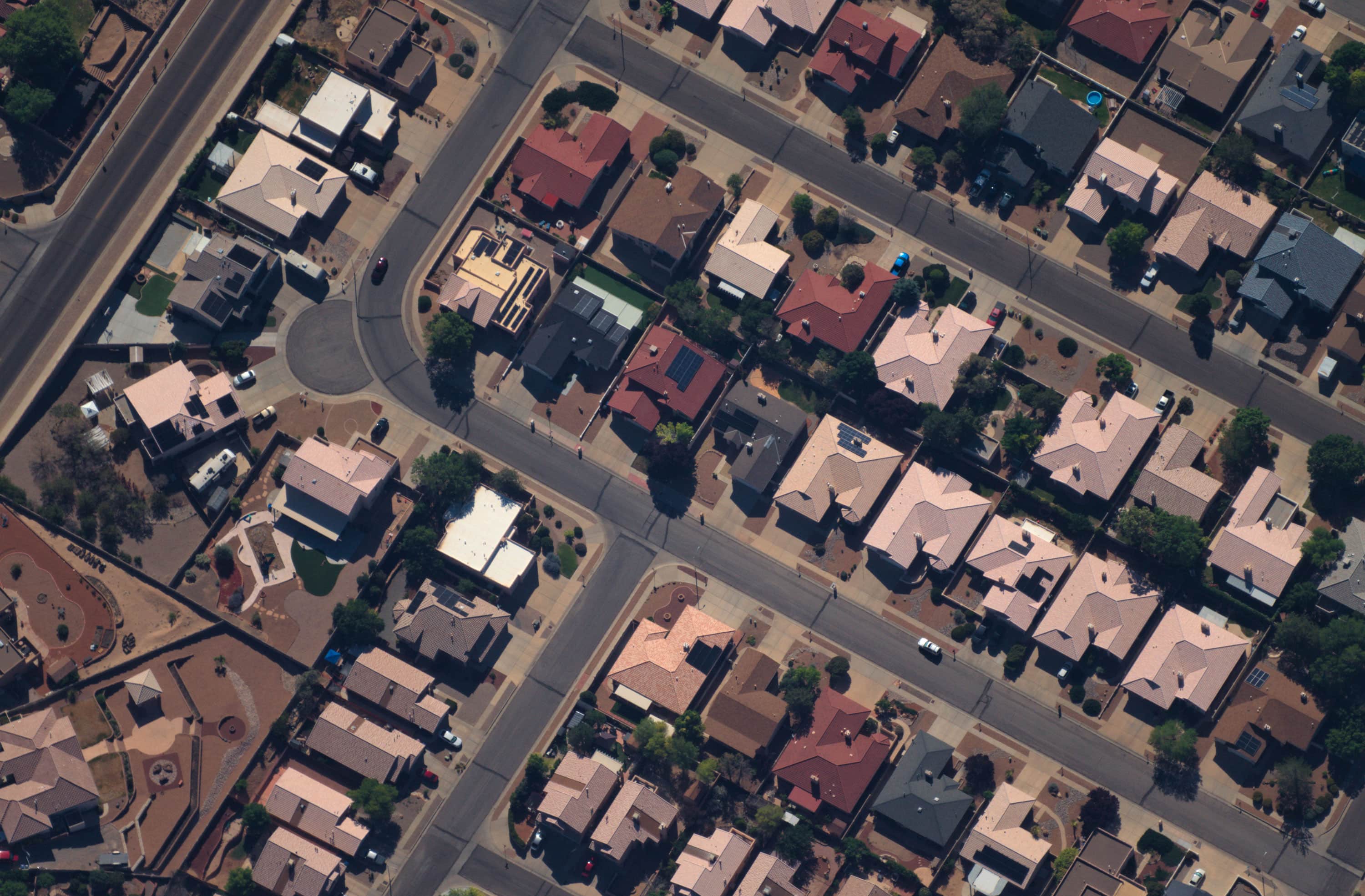 Aerial view of a suburban neighborhood with multiple single-family homes, streets, and a small playground area.