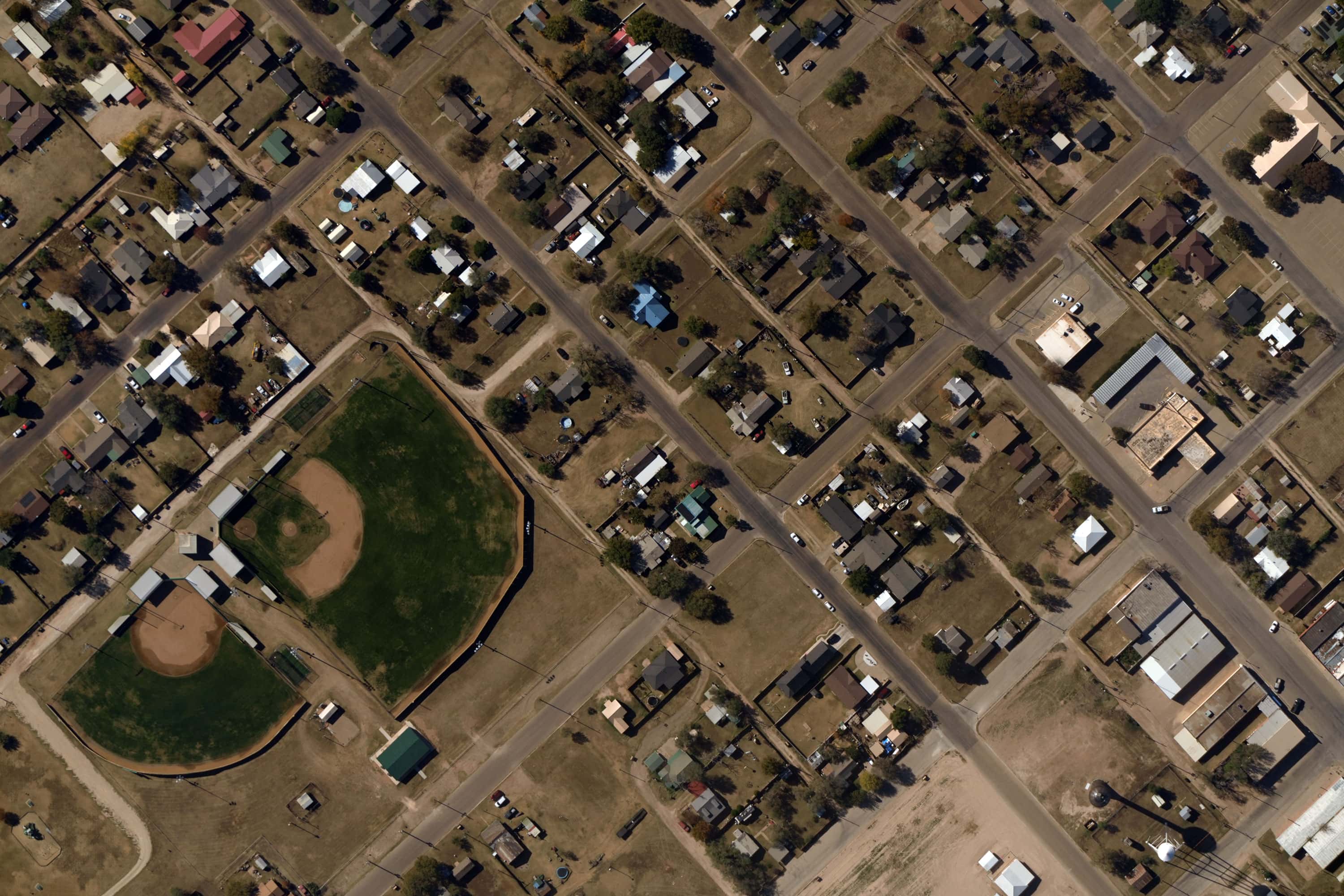 Aerial view of a neighborhood showing two adjacent baseball fields surrounded by residential houses and streets.