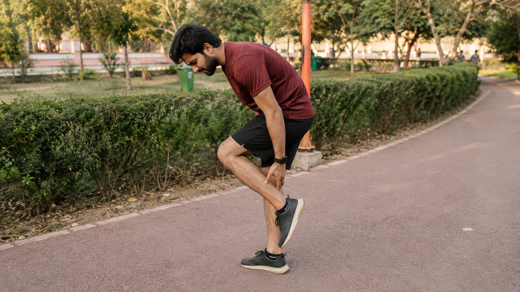 A runner stopping to hold a painful calf muscle during a run.