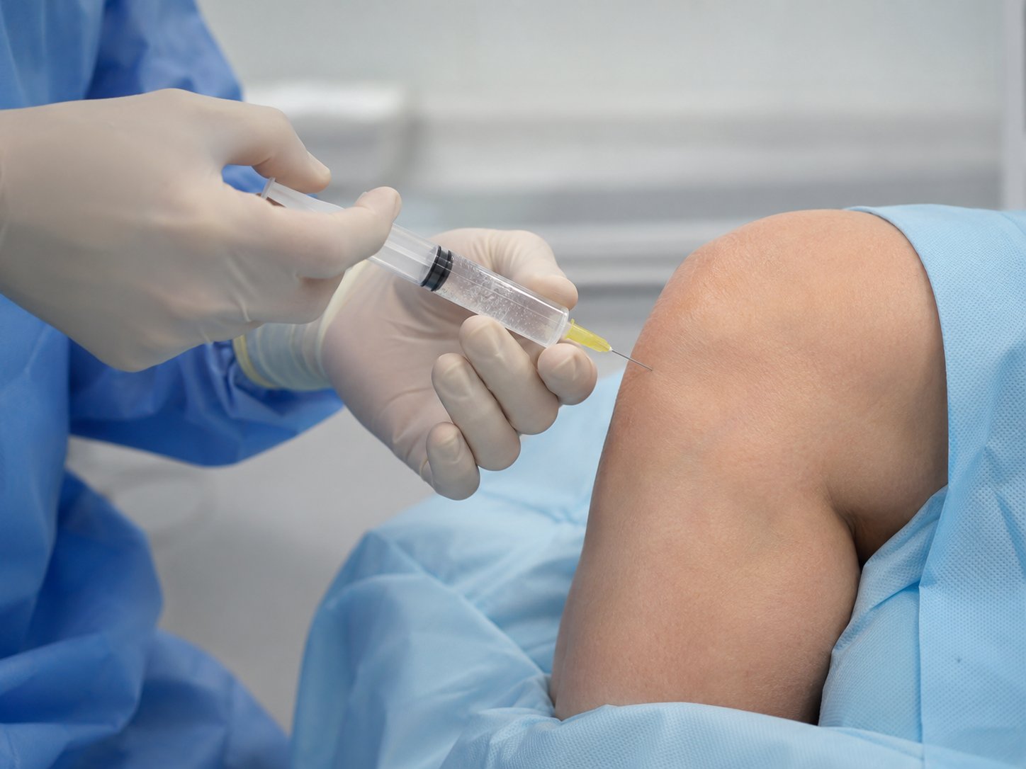 A clinician preparing a hyaluronic acid injection for an arthritic knee.
