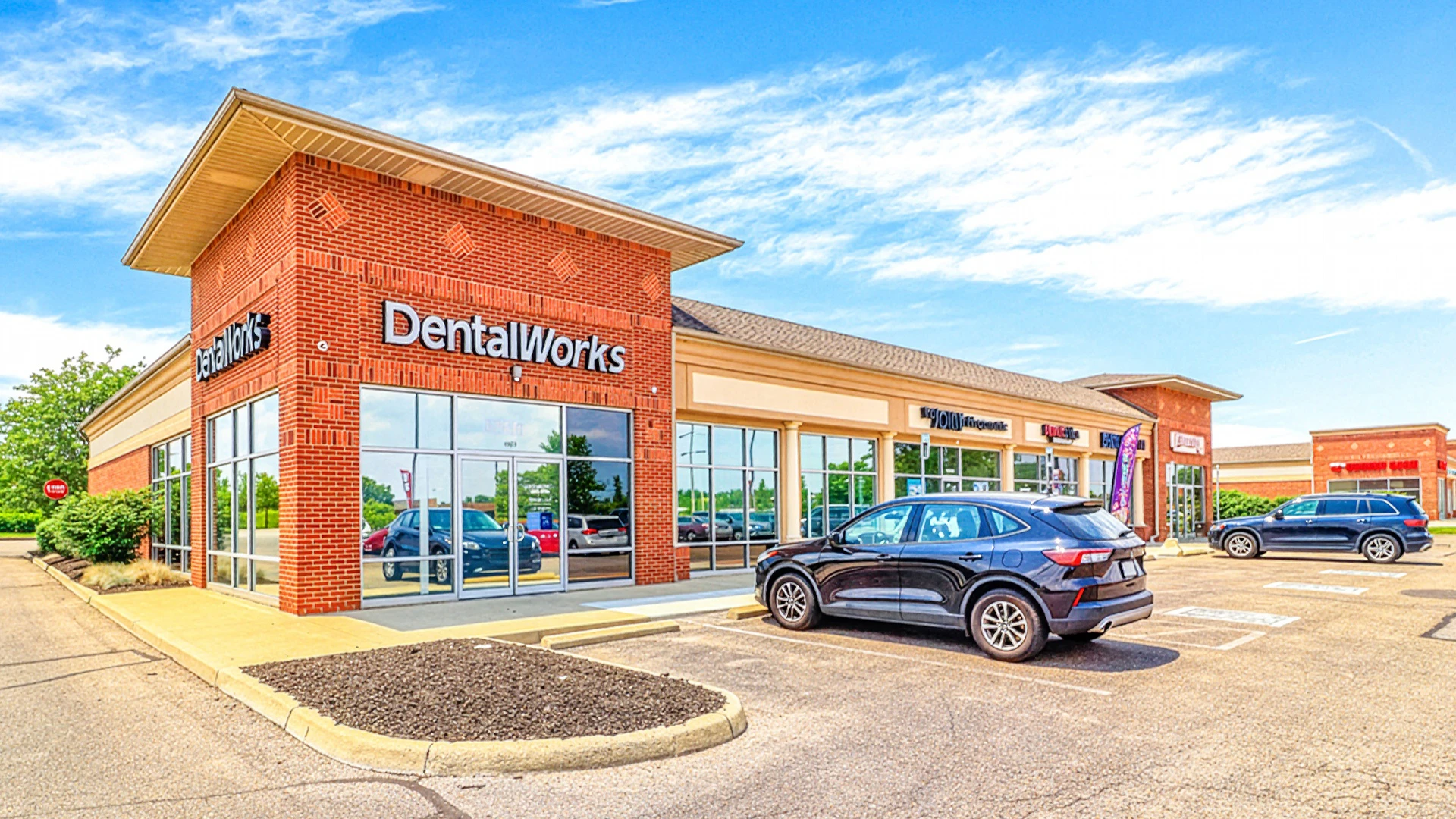Three men sitting at a table in a restaurant engaged in a conversation, two facing the camera and one with his back to the camera.