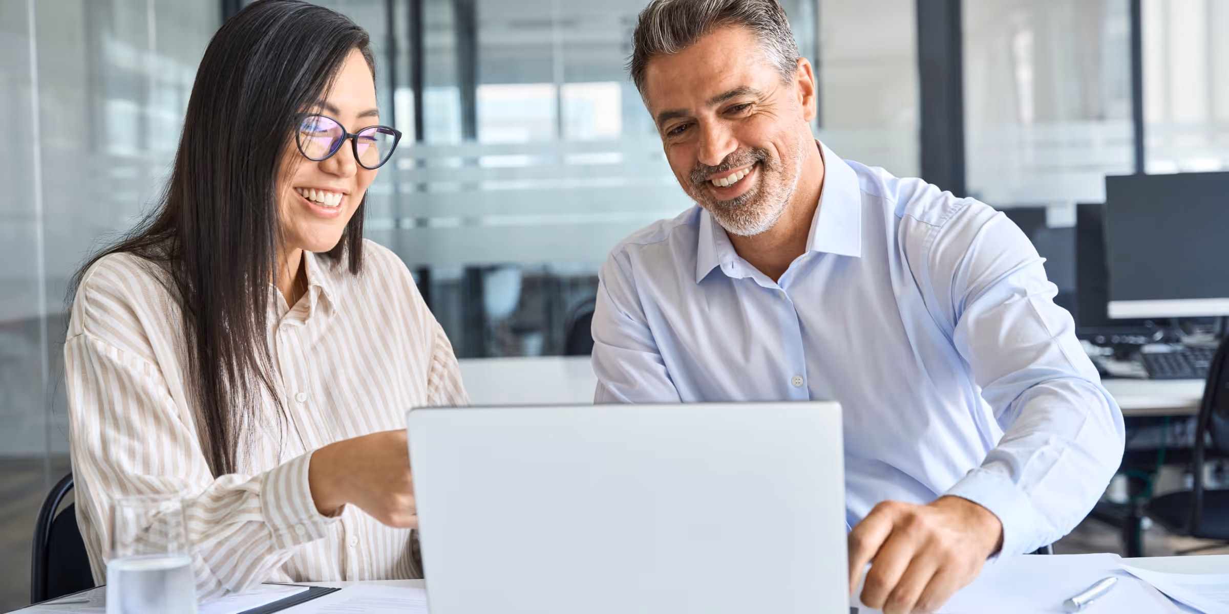 traders discussing trading strategies while reviewing charts on a laptop