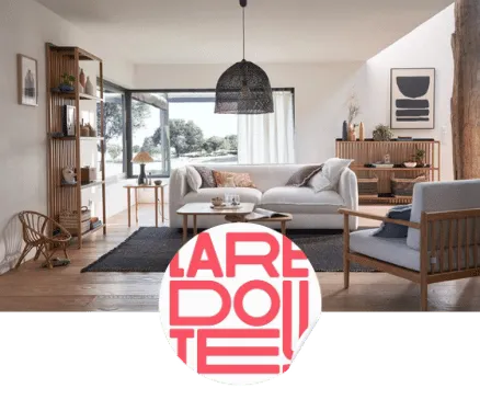 Salon lumineux avec grand canapé gris, fauteuil en bois, table basse ronde et grande baie vitrée donnant sur un jardin.