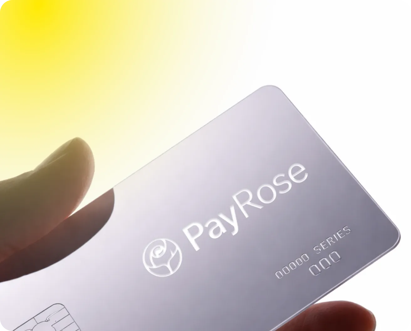 Hand holding a silver PayRose card with a rose logo and chip under bright lighting.