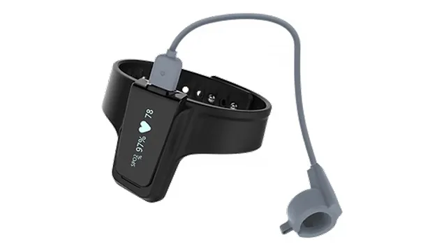 Black wrist-worn medical device with display showing oxygen saturation and heart rate, connected to a gray sensor via a cable.