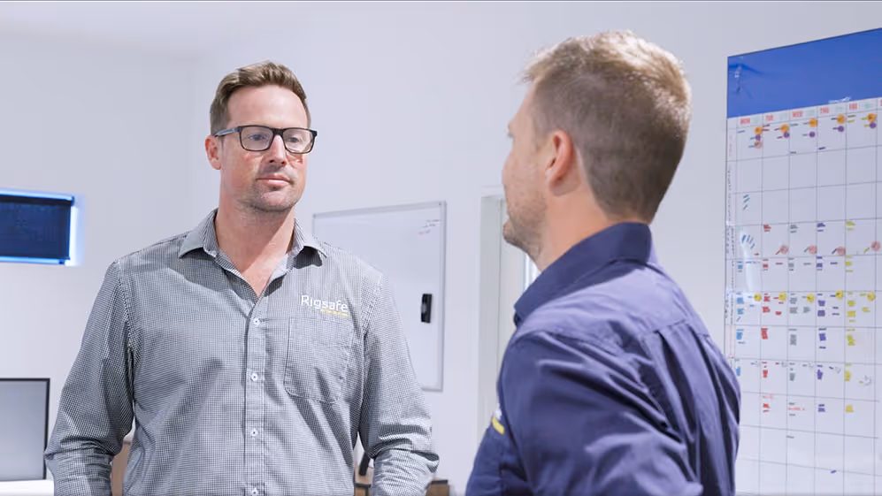 Close-up of a blue and yellow Rigsafe vehicle with 'Lifting Solutions' and safety slogan on the door.