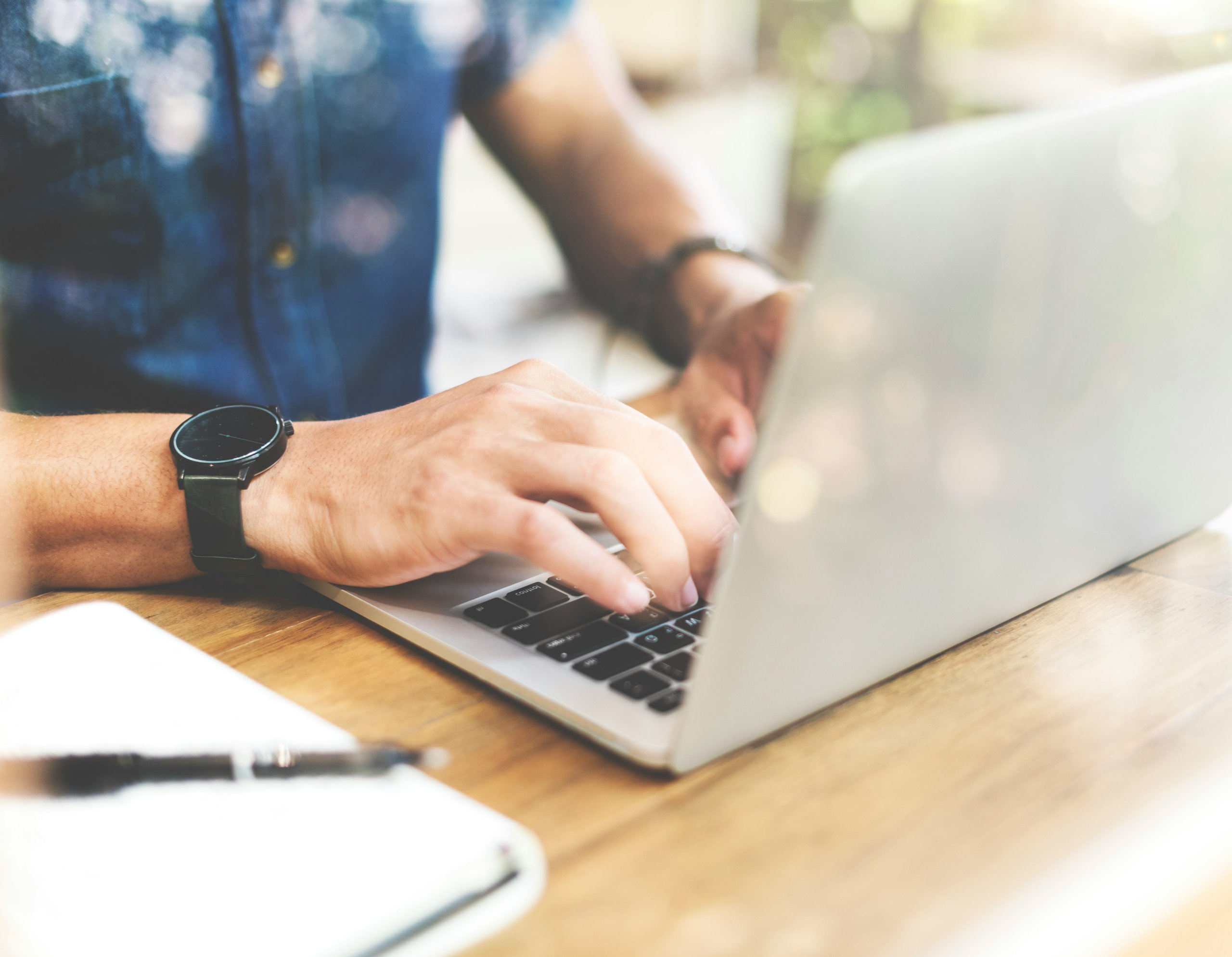 A mans hands typing on a laptop.