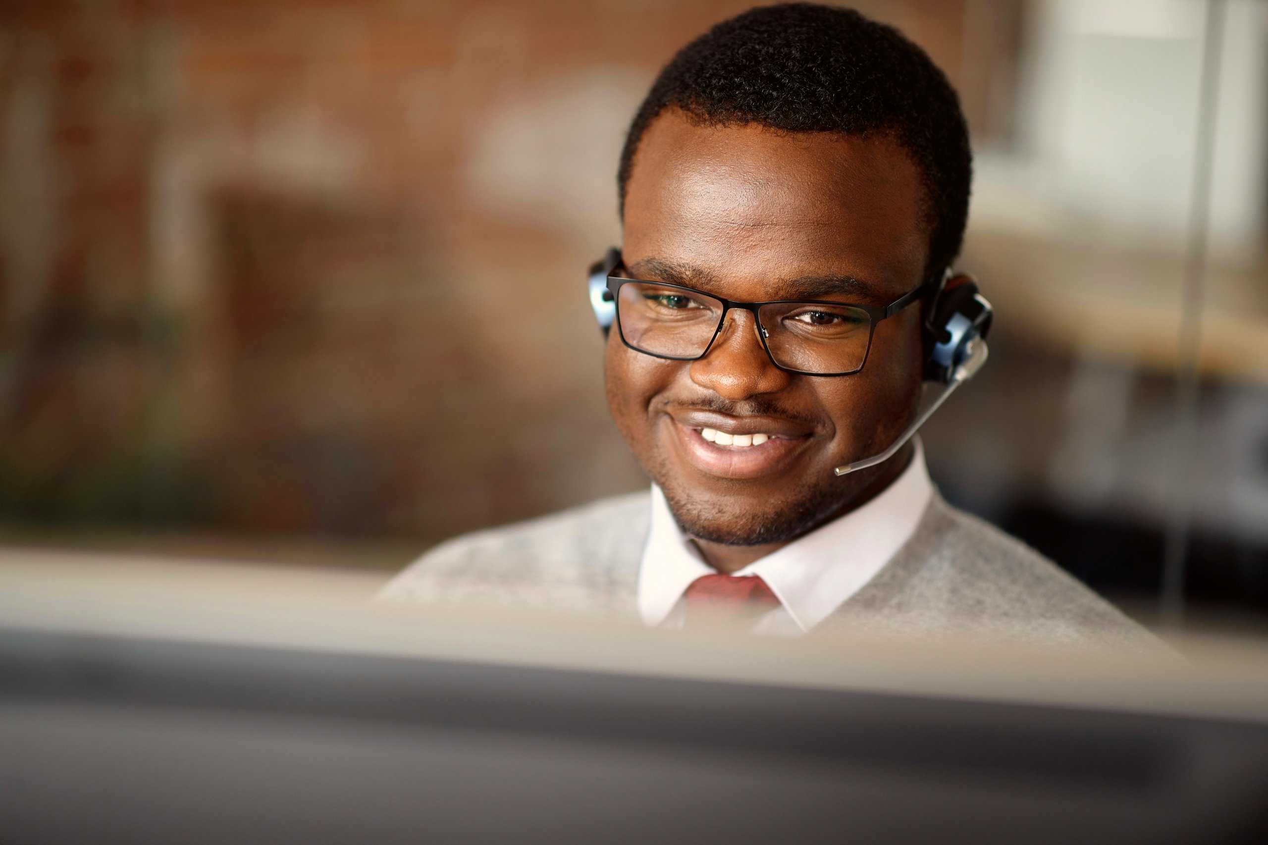 Man taking a call while looking at a computer monitor.