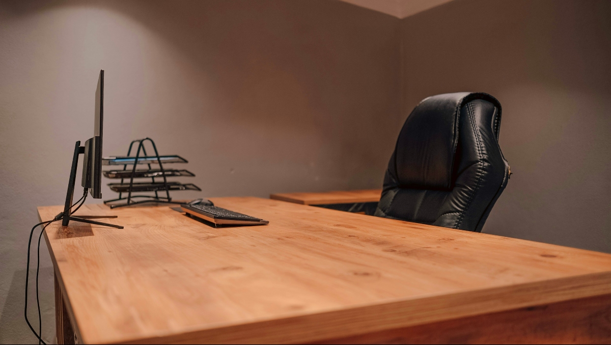 Wooden medium sized "L-shaped" desk with a computer on it. 