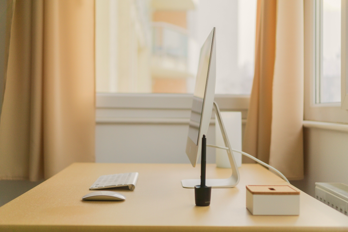 A small desk with a computer, facing a window. 