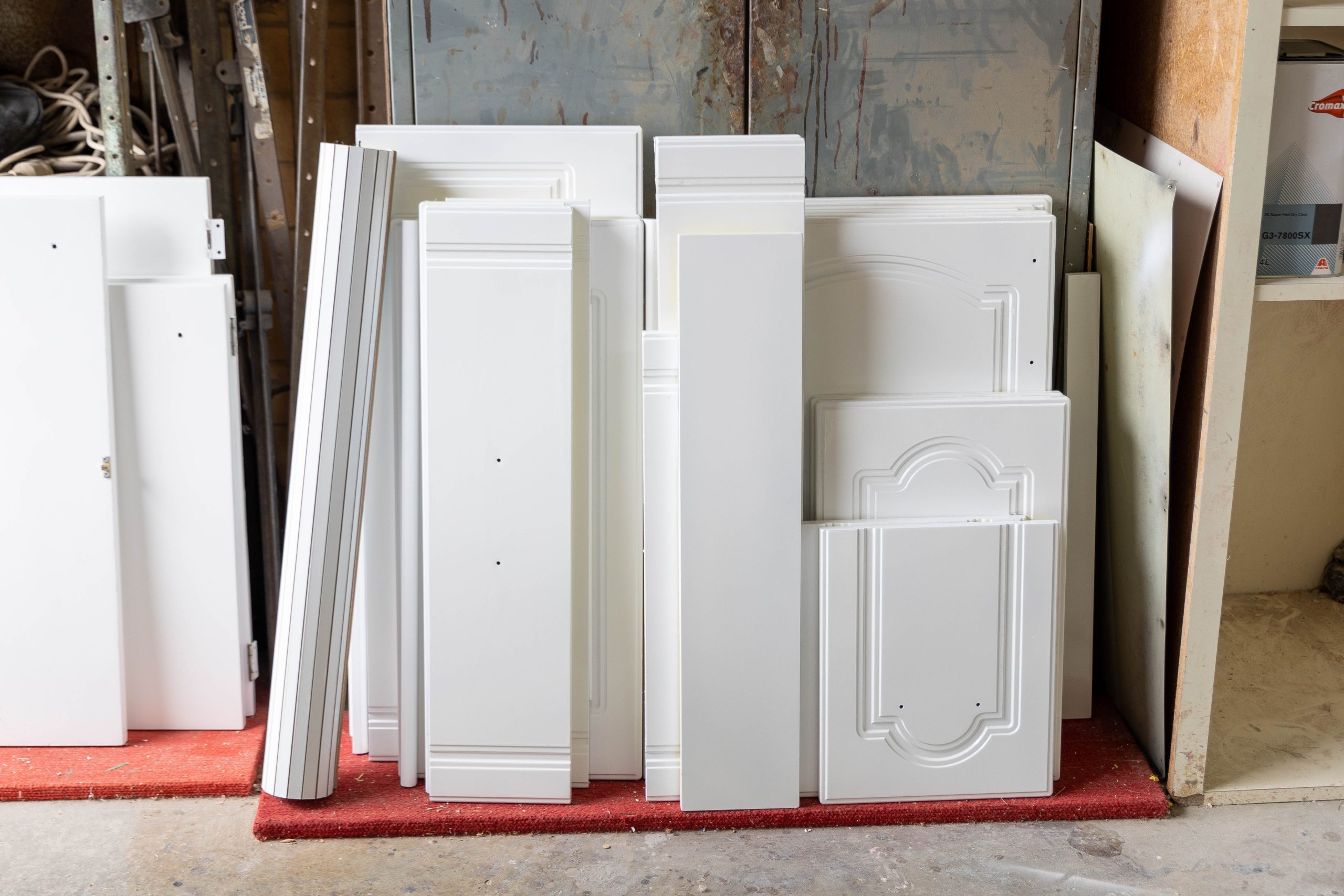 White cabinet doors and drawer fronts arranged in a resurfacing workshop