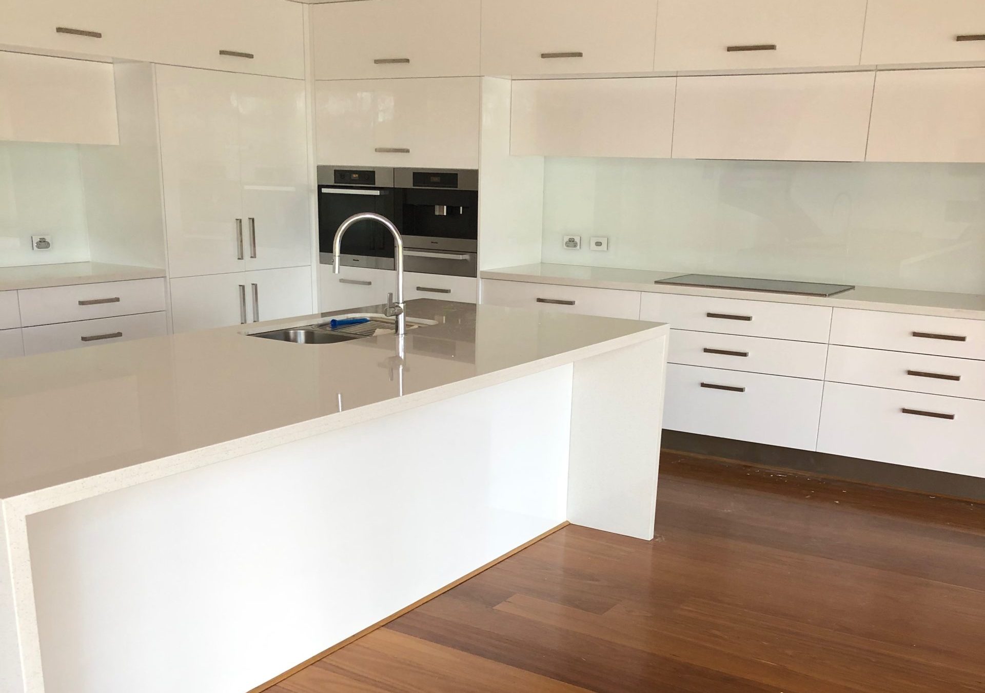 Finished white kitchen cabinetry with a pale island benchtop