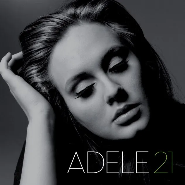 Black and white close-up portrait of Adele with eyes closed, resting her head on her hand, with 'ADELE 21' text at the bottom.