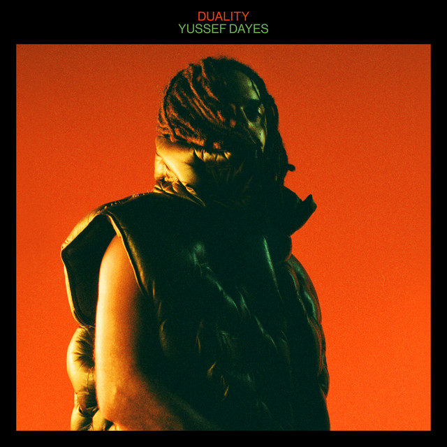 Man with dreadlocks in a black puffer vest against a dark orange background, album title 'Duality' above.