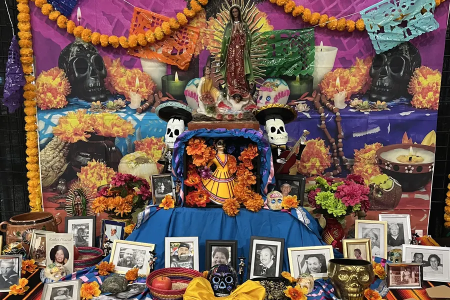 A Día de los Muertos ofrenda with marigolds, candles, sugar skulls and photographs of loved ones