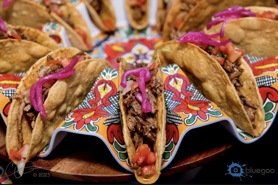 Tacos with pickled red onion and salsa on a colorful Talavera-style tray