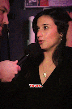 Woman speaking into a microphone held by a man, with the subtitle 'Yours.' bandkaroke.live