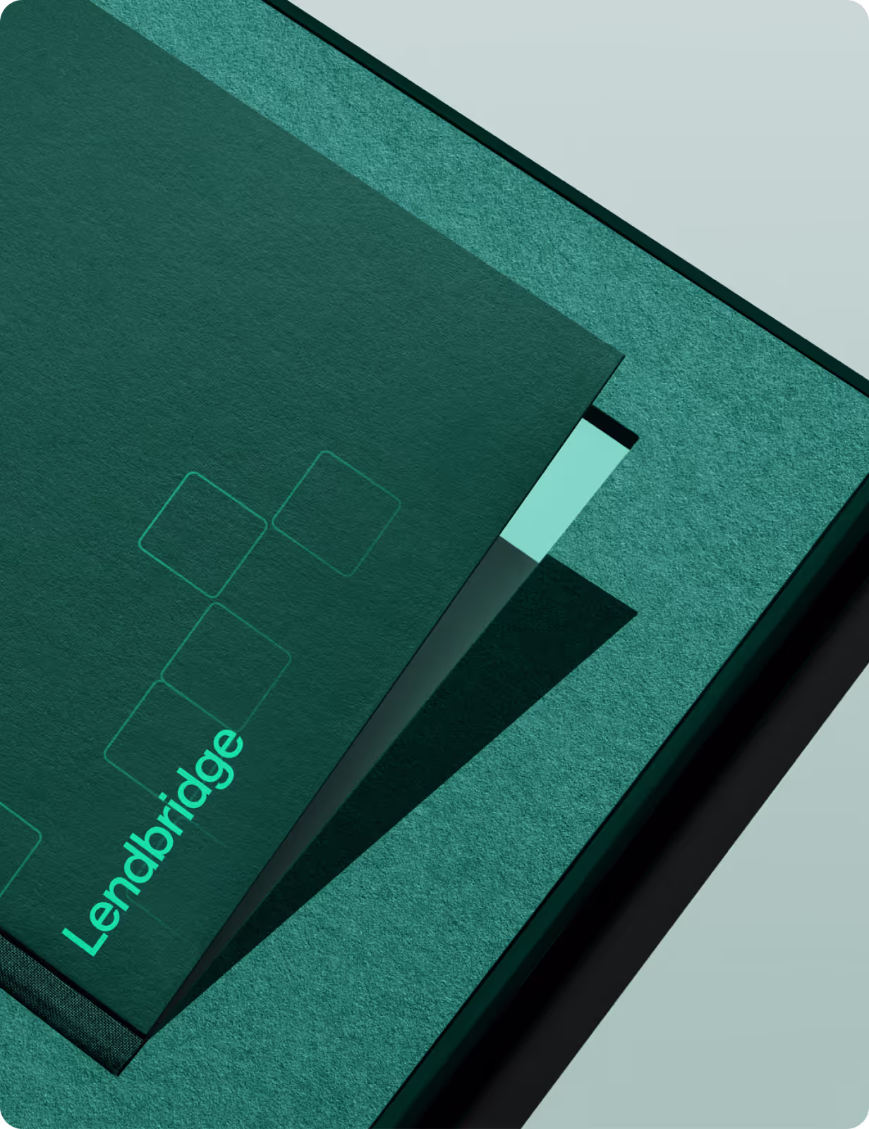 Close-up of a premium dark green Lendbridge card or folder with a textured finish, featuring the bright green wordmark and geometric square design.