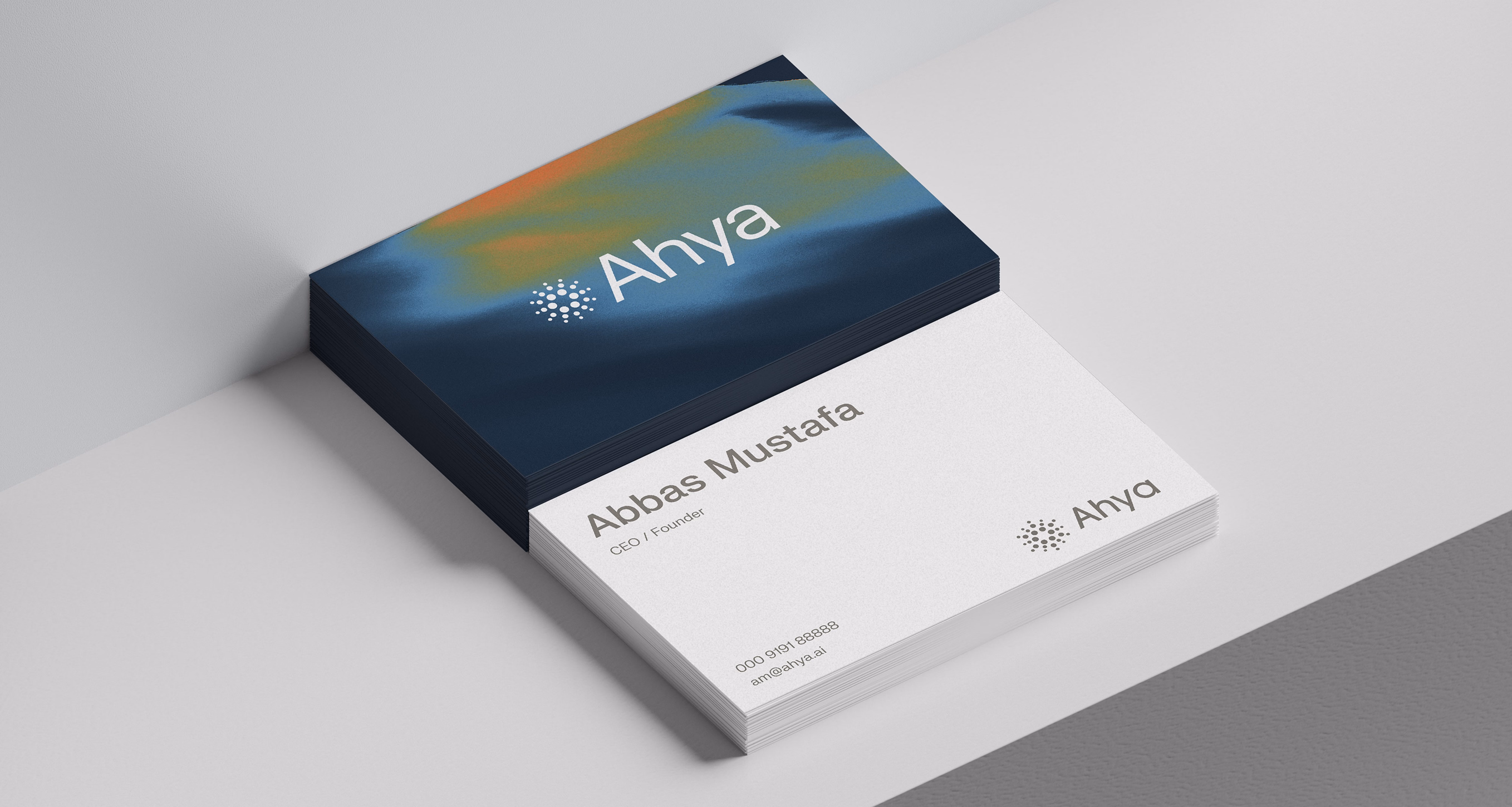 A professional mockup of Ahya business cards. One stack shows a dark blue back with a colorful heat-map graphic and the Ahya logo; the other shows the front with the name "Abbas Mustafa, CEO / Founder." 