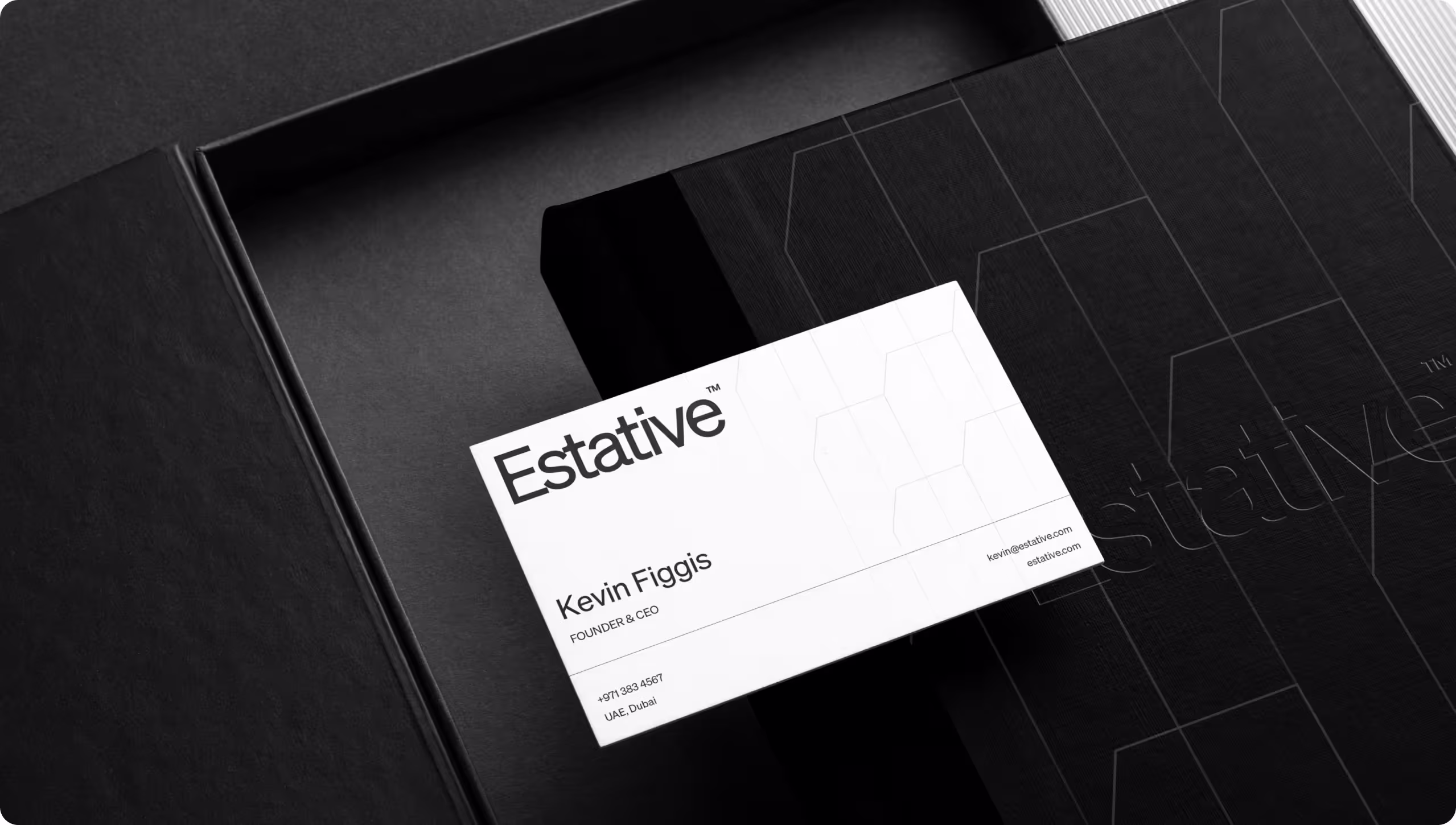 A minimalist white business card for Estative Founder & CEO Kevin Figgis, placed inside a premium black presentation box with embossed brand detailing. 
