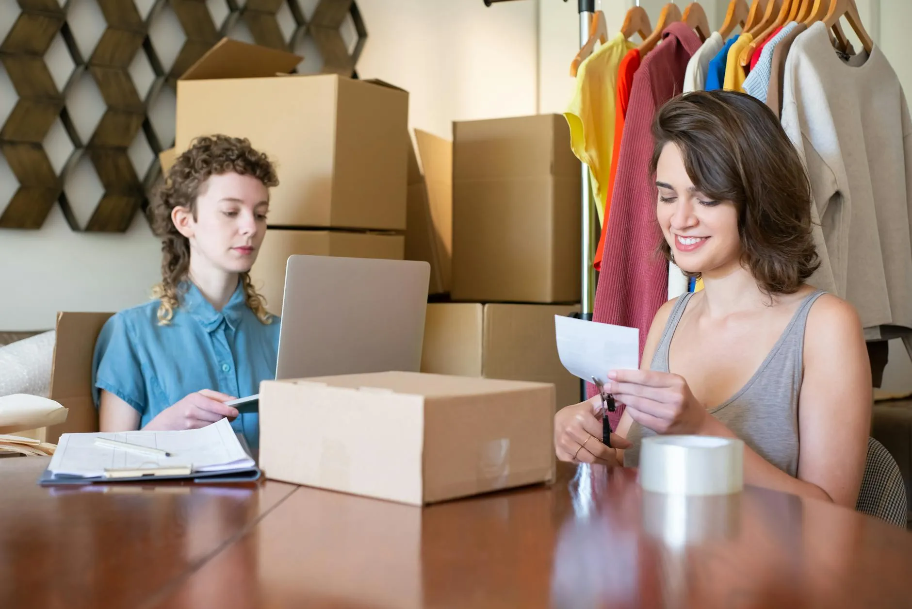 Two women organize and manage an online store with boxes and a laptop - a symbol of everyday life as a seller on Amazon.
