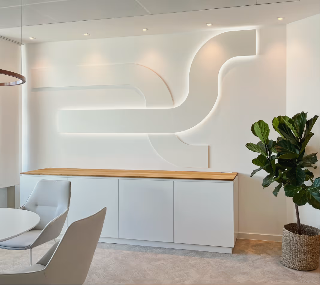 Modernes Büro mit weißem Sideboard, dekorativer Wandbeleuchtung und grünem Pflanzenkorb.