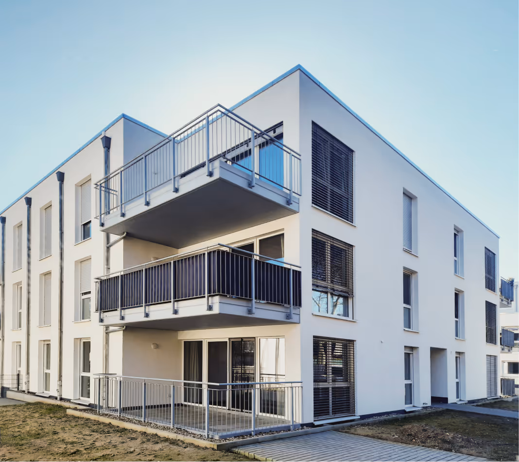 Modernes zweistöckiges Wohngebäude mit Balkonen und großen Fenstern bei klarem Himmel.
