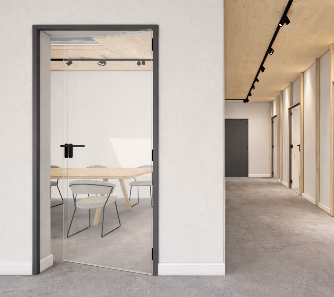 Moderner Büroflur mit grauem Teppich, Glastür zu Sitzungsraum mit Holztisch und Stühlen.