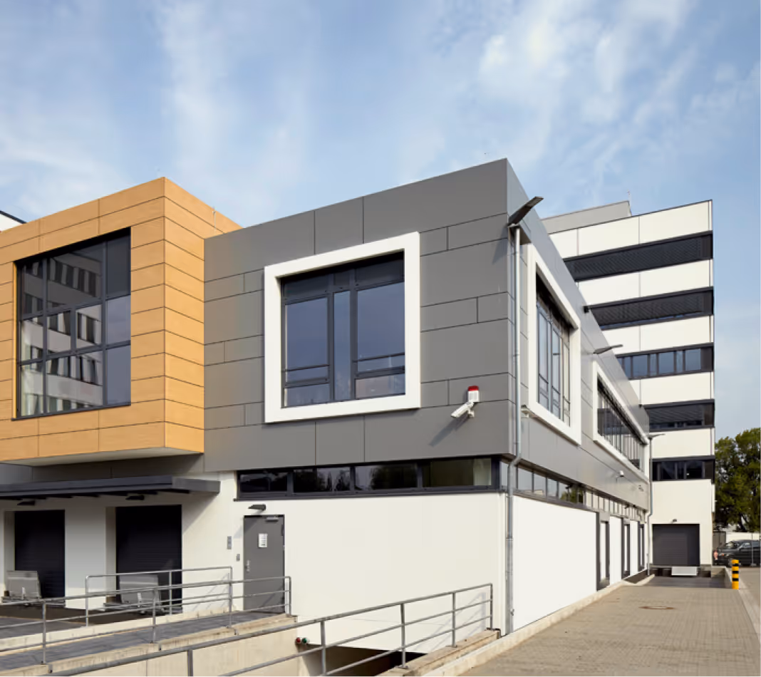 Modernes Bürogebäude in Grau, Weiß und Orange mit großen Fenstern und Rampe.