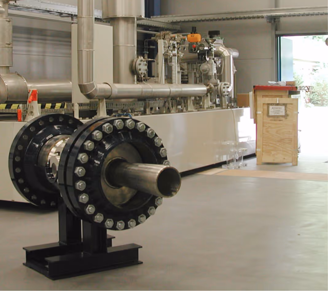Industrielle Rohrleitung mit verstärkter Verbindung und Metallstütze in Werkhalle.