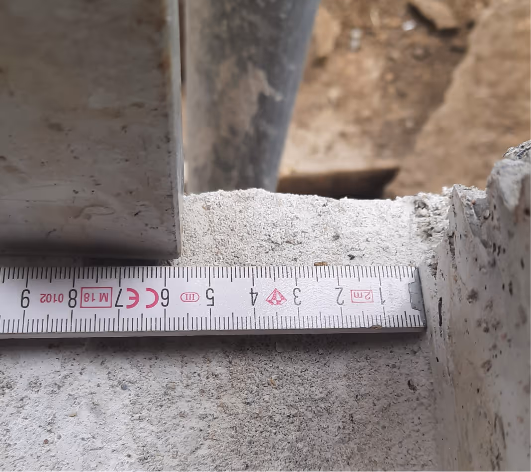 Messband zeigt Abmessung von etwa 8 Zentimetern auf Betonoberfläche zwischen zwei Bauteilen.