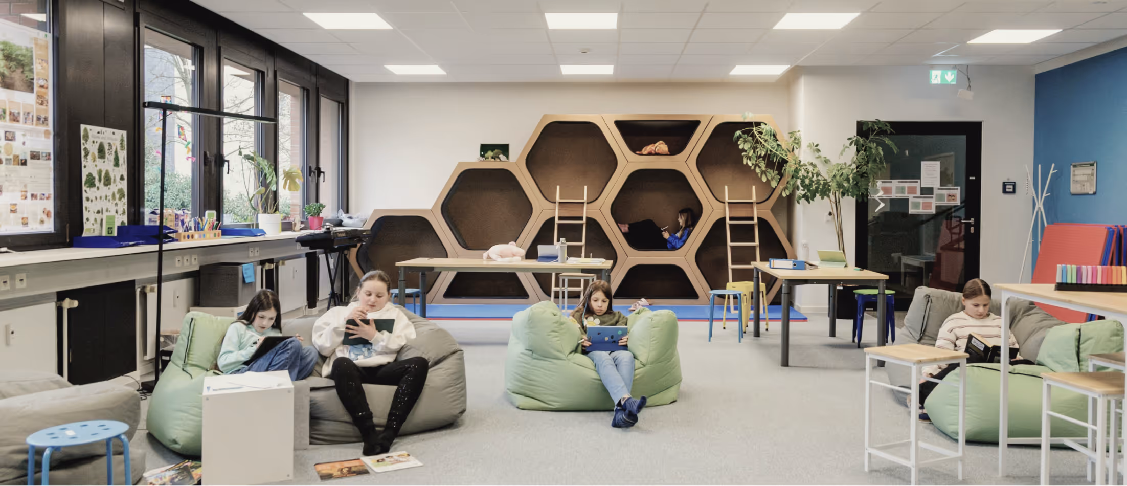 Moderner Lernraum mit Sitzsäcken, Arbeitsplätzen und Kindern beim selbstständigen Lernen.
