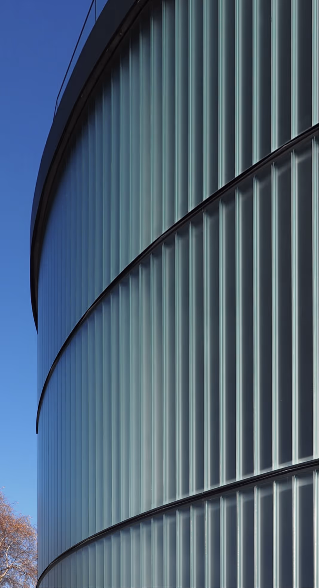 Moderne Gebäudefassade mit geschwungenen Linien und vertikalen Glaselementen als Beispiel zeitgenössischer Architektur.
