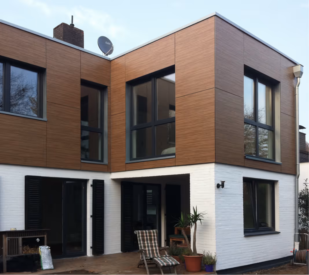 Modern mehrstöckiges Haus mit weißen Wänden, großen Fenstern und schwarzem Cabrio auf der Einfahrt.