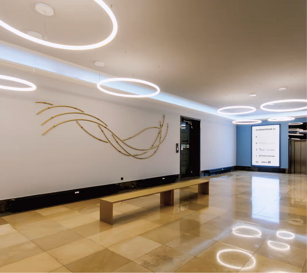 Moderner Eingangsbereich mit heller Natursteinoptik, Sitzbank und indirekter LED-Beleuchtung.