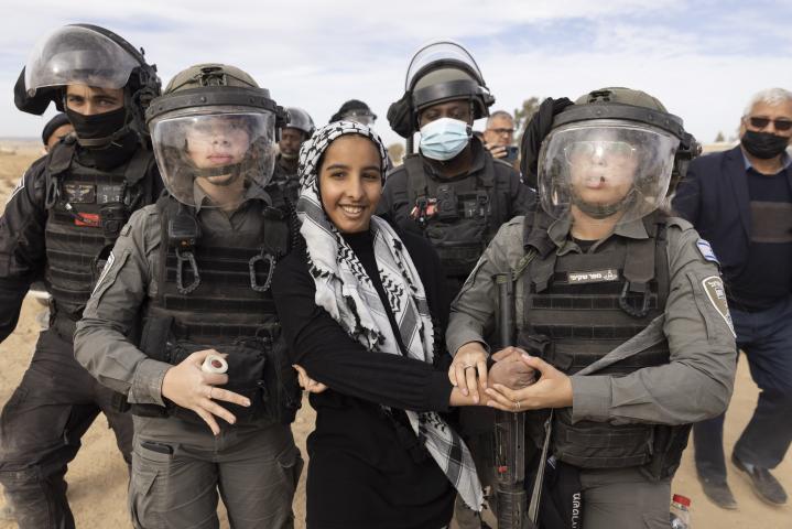 A young Palestinian girl smiling while being arrested by the occupation forces of Israel