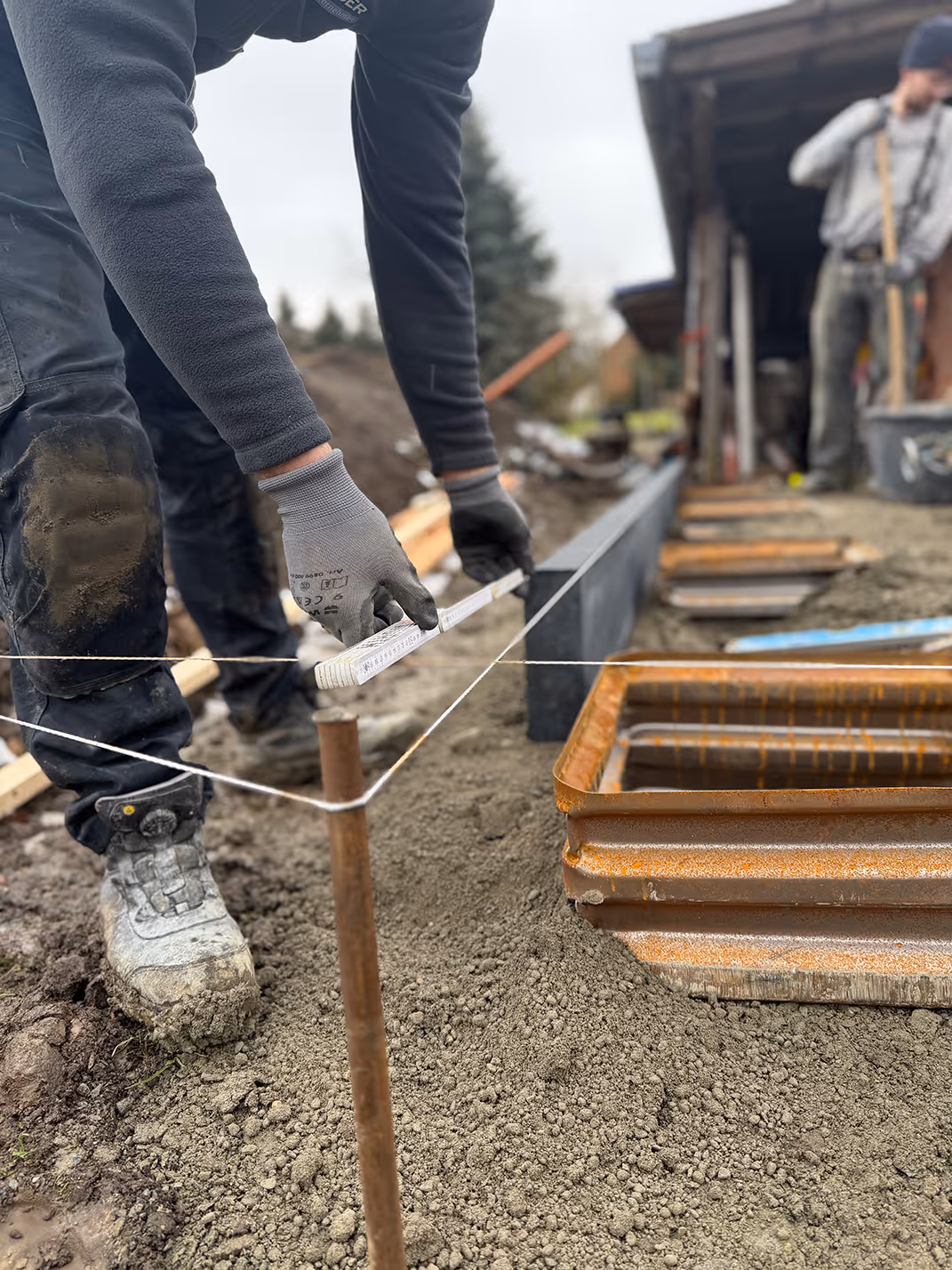 Bauarbeiter spannt eine Richtschnur an einem Holzpfahl auf der Baustelle
