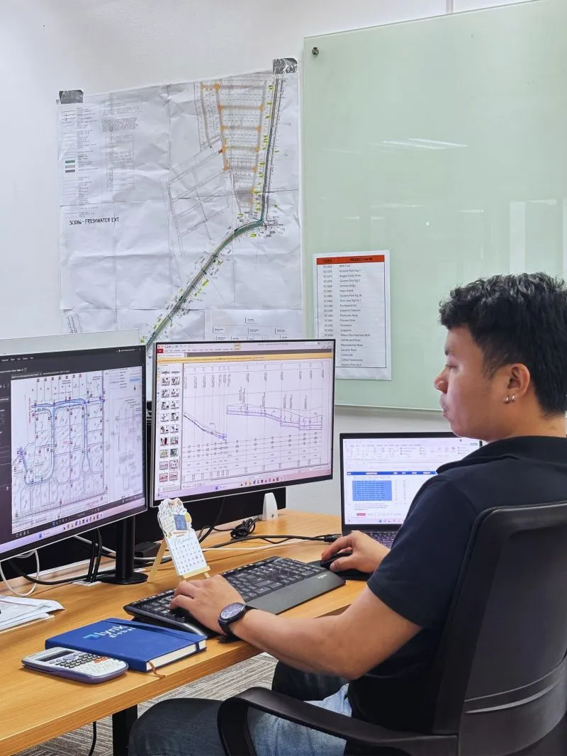 Lynk team member reviewing construction drawings at a dual-monitor workstation.