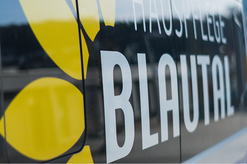 Close-up of a glass surface with the text 'BLAUTAL' and part of a yellow flower logo.