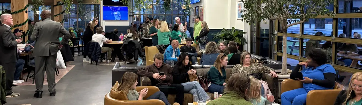 Indoor gathering at a Huntersville bar with hanging plants, lounge seating, and groups socializing during trivia night