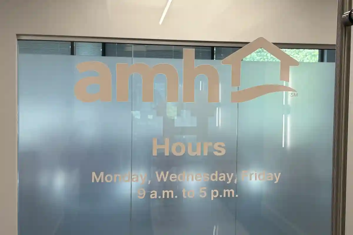 AMH office door with logo and posted business hours on glass entrance 