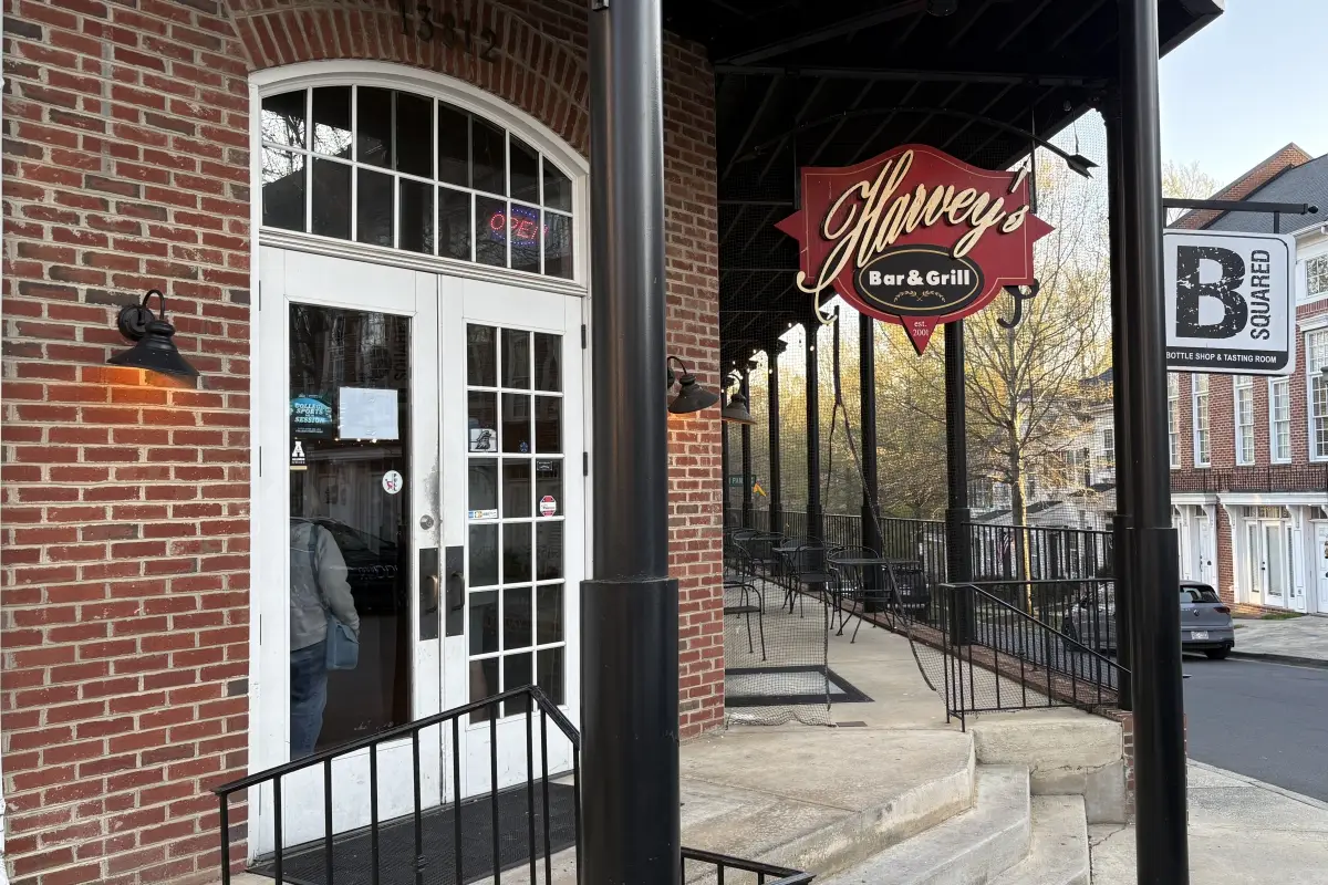 Entrance to Harvey’s Bar & Grill with outdoor patio seating and hanging sign 